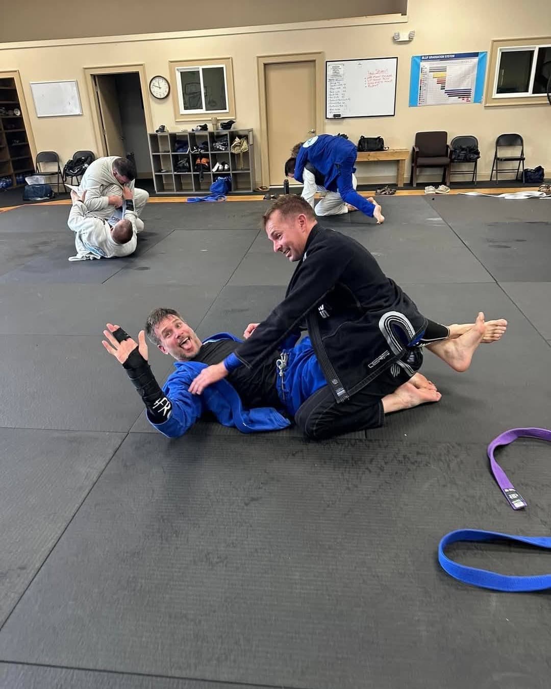 Tim Erway getting pinned during Brazilian Jiu-Jitsu training, waving at the camera